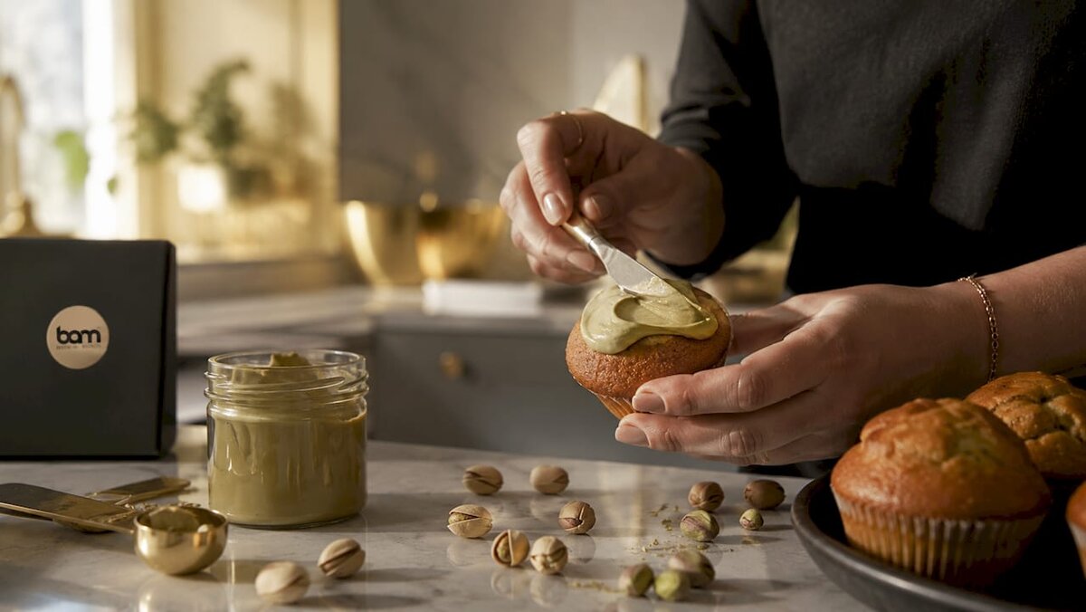 Ręce nakładające pastę pistacjową na muffinkę